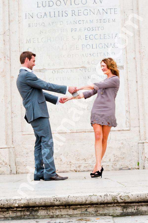 Dancing at Spanish steps in front of a marble wall with Latin writing on it.