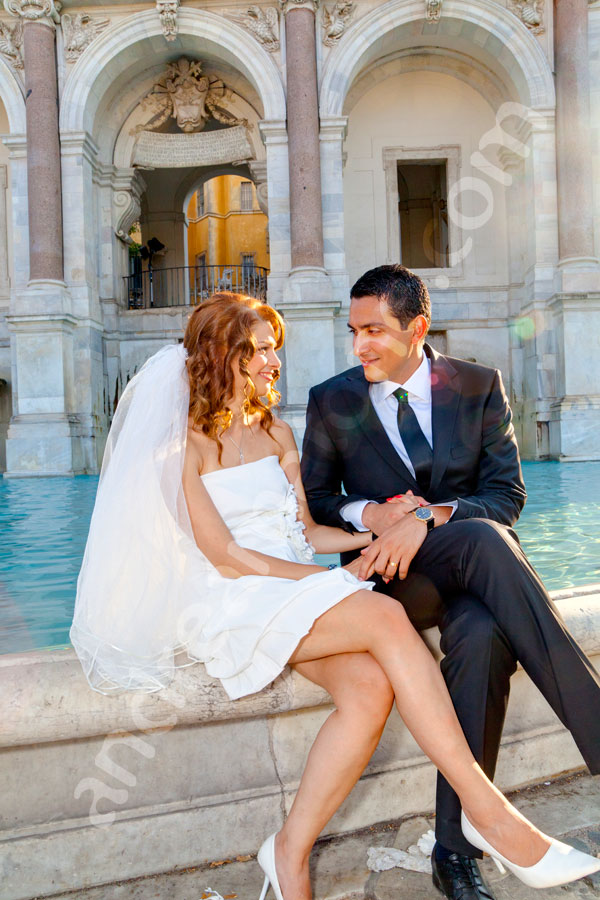 The bride and groom sitting on the edge of Fontana Fontanone del Gianicolo 