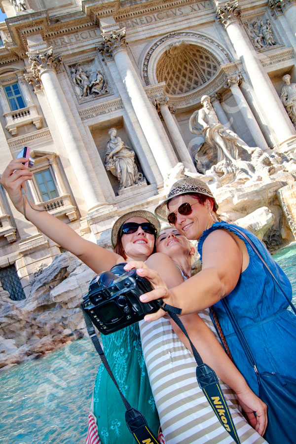 Tourists photographers taking a funny picture of themselves in Piazza Fontana di Trevi. Vacation pictures.