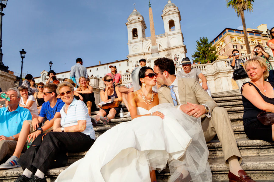 Best Wedding Photographers in Rome Italy. The bride and groom romantically kissing among tourists on the Spanish steps.