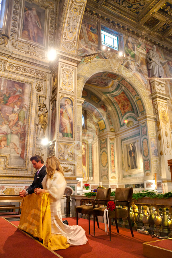 Bride and groom kneeling down by the alter during their wedding ceremony.