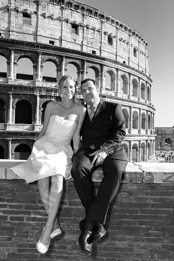 The Coliseum. Man and woman in matrimonial attire sitting on a wall.