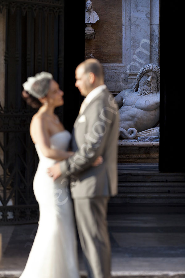 Newlyweds kissing in front of the Campidoglio statue. 