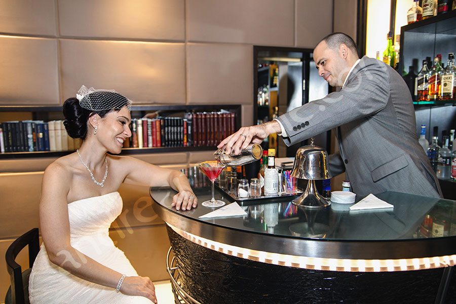 The groom bartender preparing a drink for the bride behind a bar