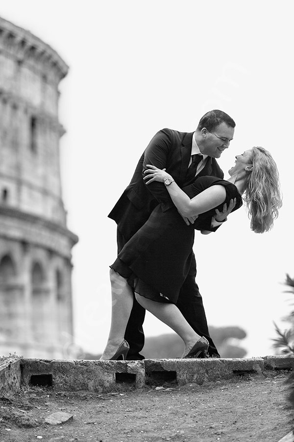 Black and white pose by the Coliseum. Man dipping woman.