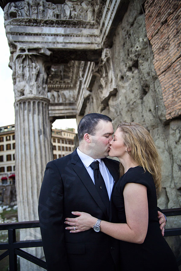 Couple kissing underneath roman ruins in Rome