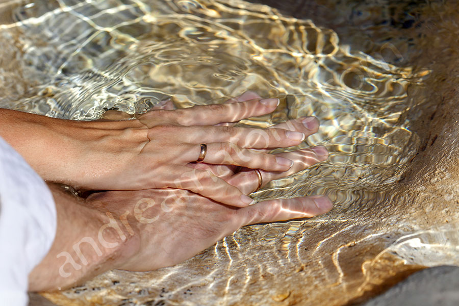 Married couple holding hands underneath the water in a fountain Villa Borghese
