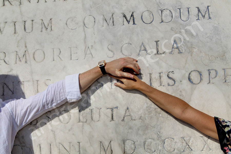 Holding onto each other's arms in front of marble slab 