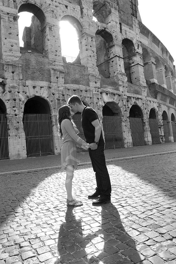 Black and white image of a man and a woman kissing in front of the Colosseum. Romantic Photo Love Story Rome Italy