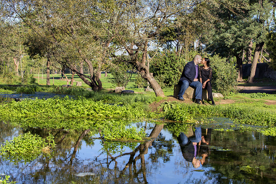 Kissing at a park and pond with the reflection in the water. 