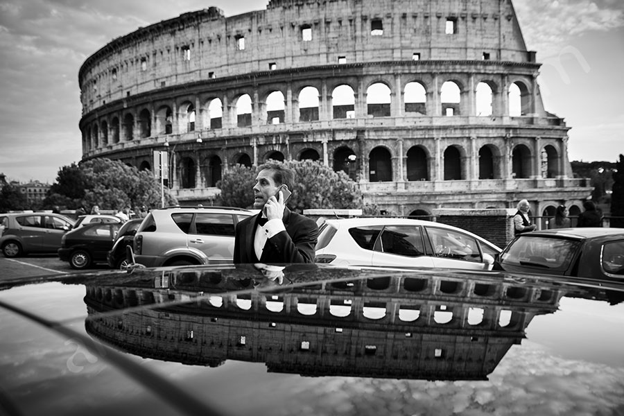 Groom talking on the phone outside the Roman Colosseum 