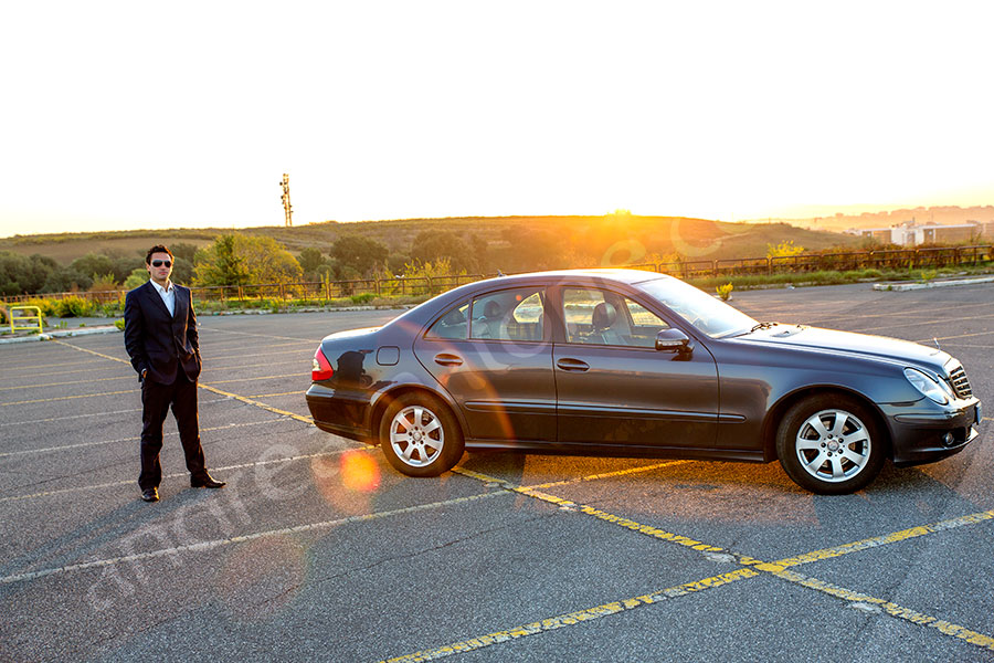 Car driver standing next to his car for hire Mercedes e series in Rome