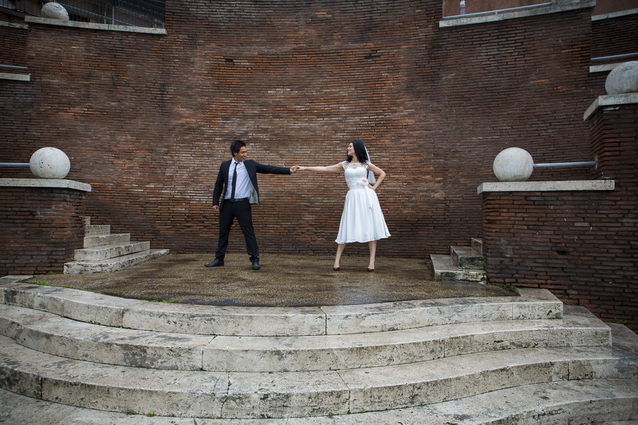 Bride and groom touching hands on Via dei Fori Imperiali in Rome