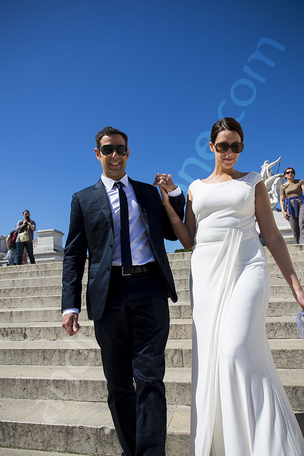 Bride and groom walking hand in hand down the stairs of the Vittoriano monument