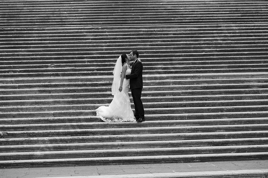 Newlyweds couple kissing on the stairs of Piazza del Campidoglio