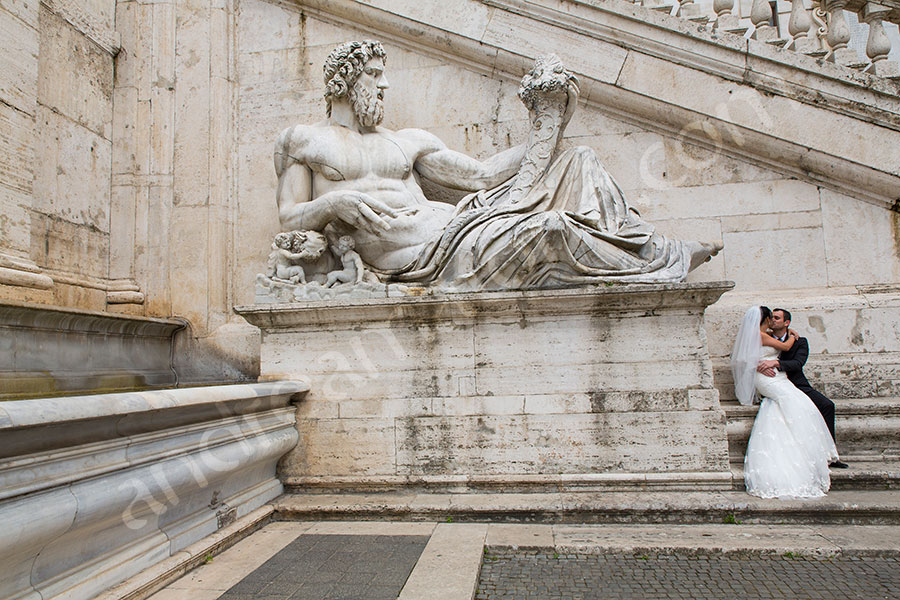 Bride and groom photographed next to a statue in Piazza del Campidoglio