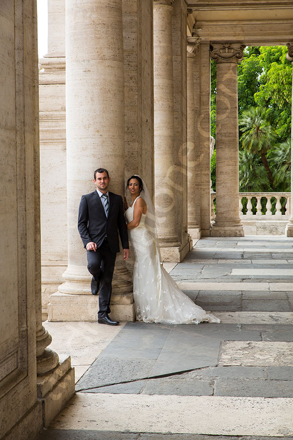 Newlyweds posing underneath columns found in Piazza del Campidoglio