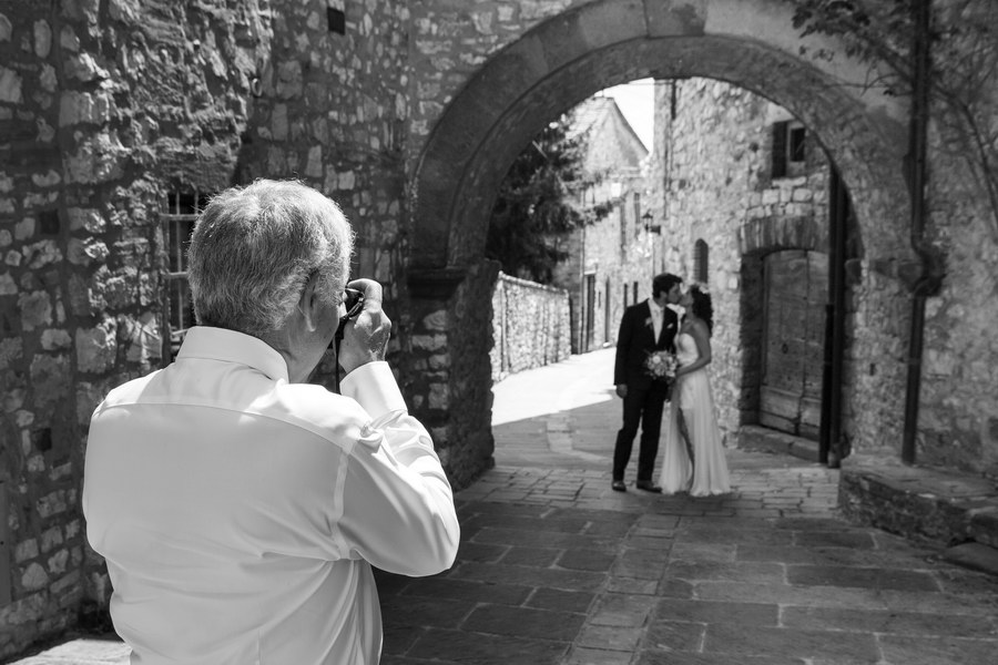 Photographer taking a picture of the newlyweds in black and white