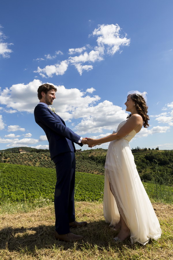 Just married couple holding hands over the beautiful Italian countryside.