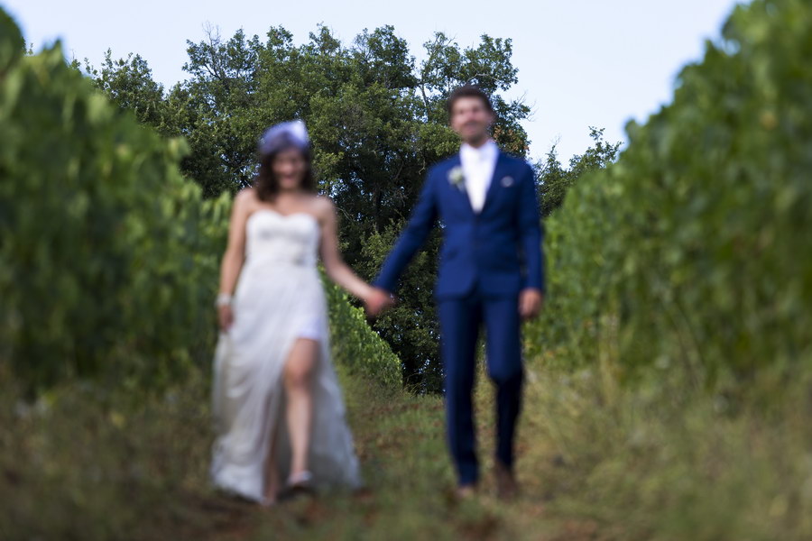 Picture out of focus as newlyweds walk in a vineyard in Italy