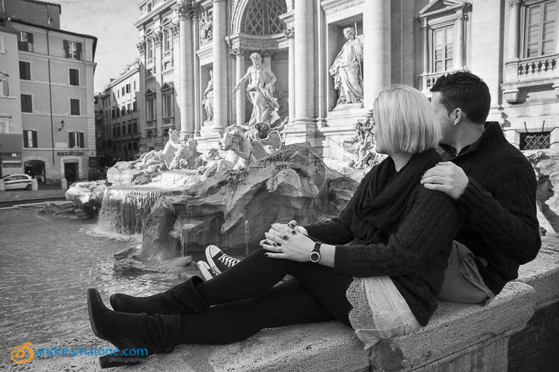 Couple looking at the Trevi fountain in black and white. 
