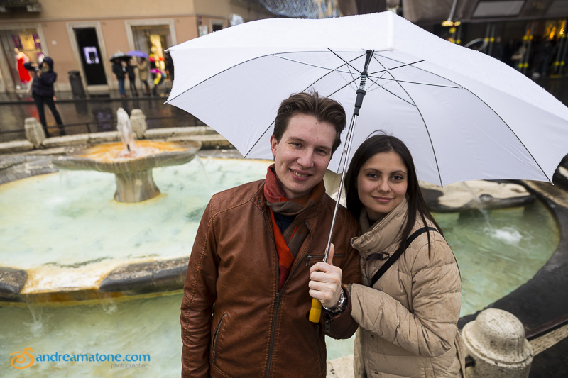 An engagement couple at the Spanish steps fountain with an umbrella.