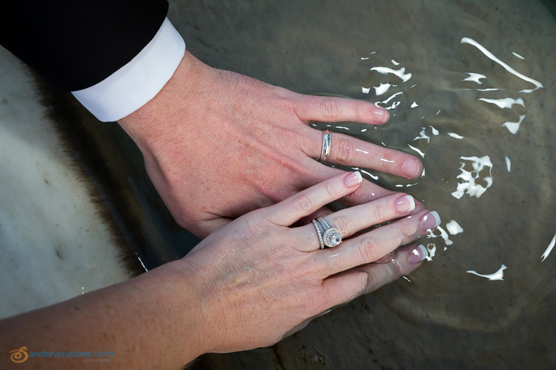 The hands of the newlyweds in the water.