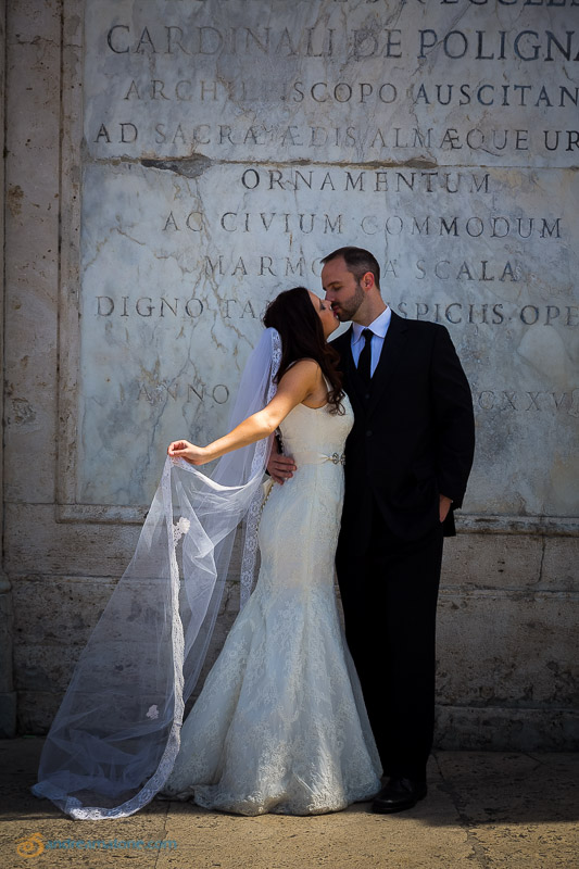 Kissing in front of an ancient marble slab.