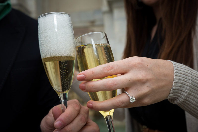 Close up picture of hands holding champagne glasses with the ring showing