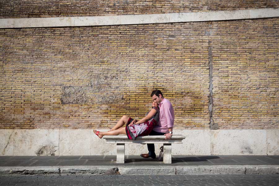 Engaged couple sitting down on a marble bench