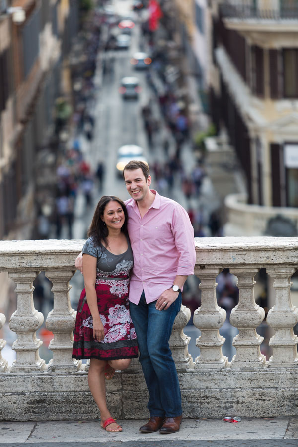 Portrait picture of a couple standing before via Condotti on the Spanish steps.