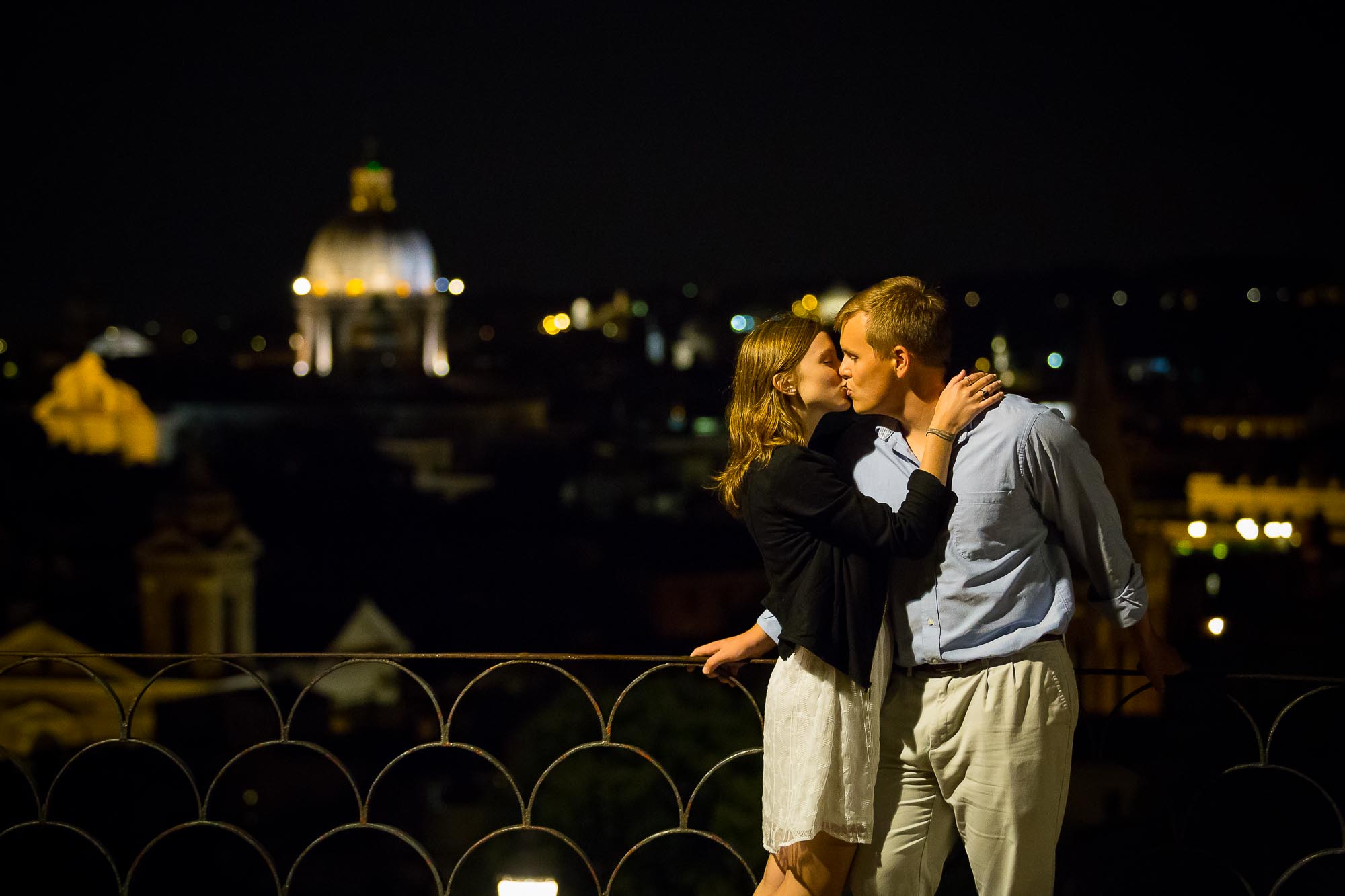 Kissing in love before the roman rooftops at night.