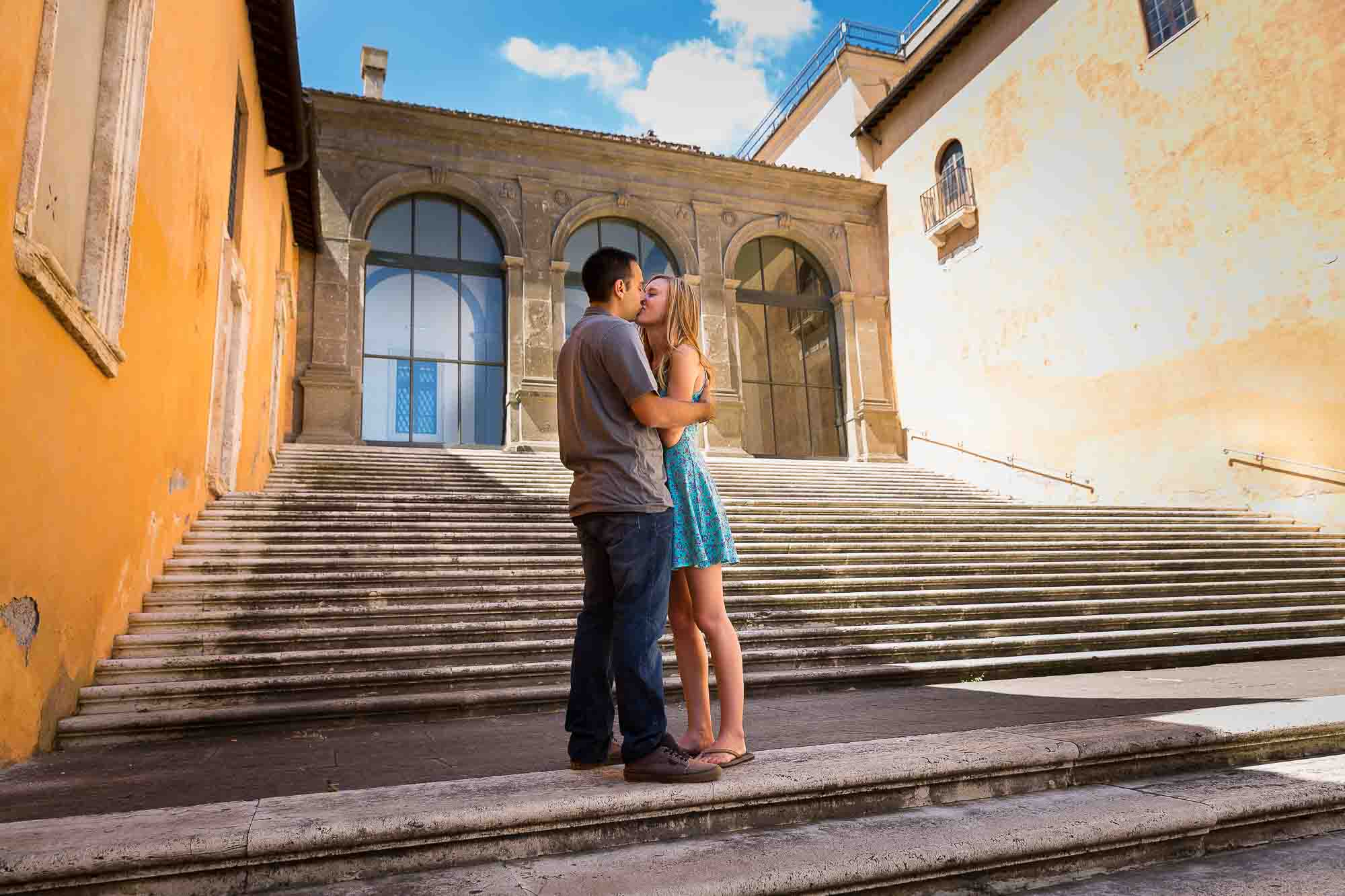 Engaged couple kissing on the steps of the Campidoglio Piazza