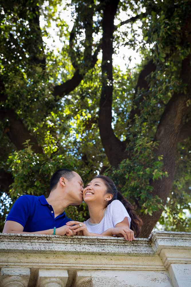 Kissing under a tree in Villa Borghese park.