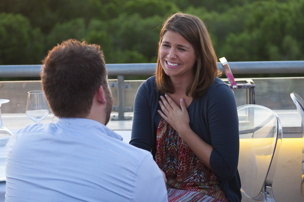 Joyful reaction to a wedding proposal question asked on top of a restaurant. Engagement Proposal Photography.