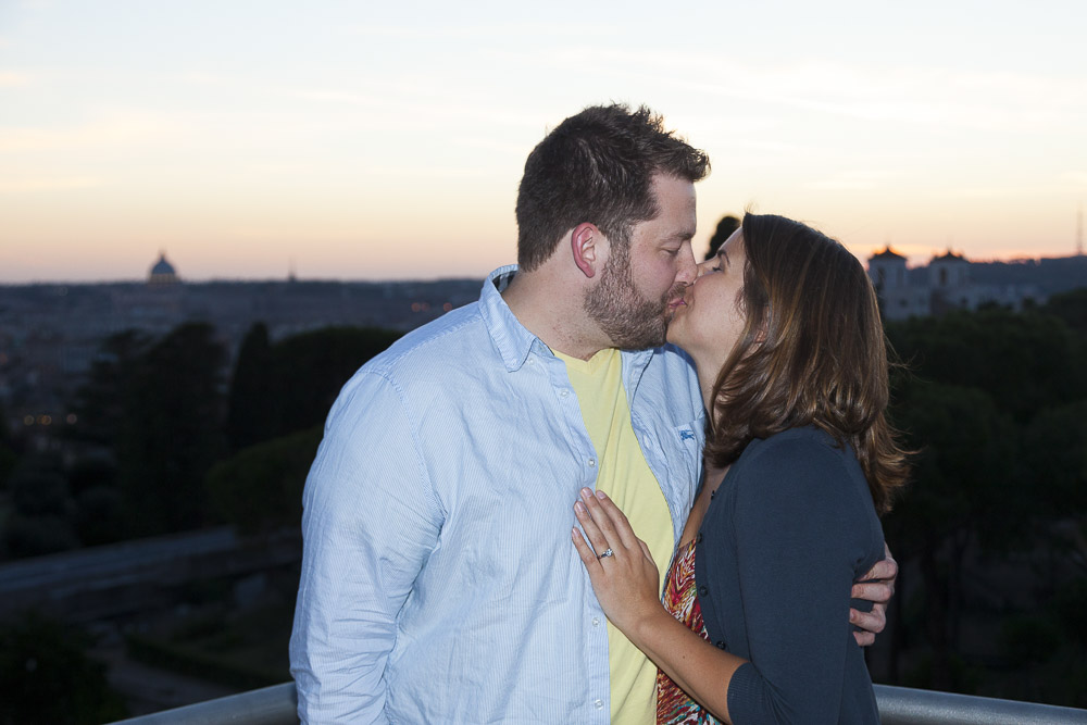 Couple kissing on top of a restaurant with a stunning view over the rooftops.