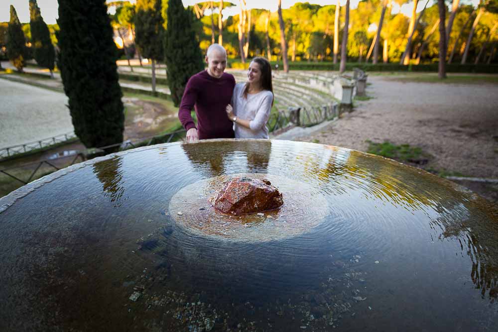 Couple portrait picture around a circular water fountain with the reflection. 
