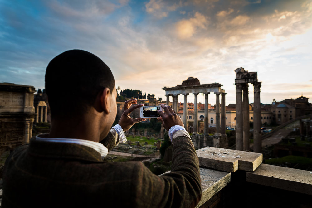 Man taking a picture of the roman forum at sunset