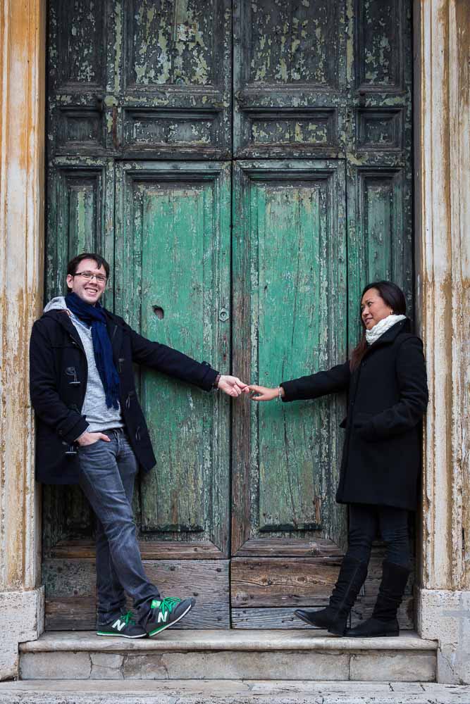 Portrait image of an engaged couple in front of a worn down green door
