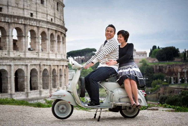 Couple sitting down on an antique Vespa moped during their wedding engagement shoot in Rome