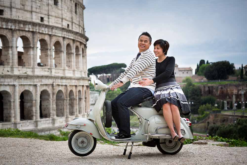 Couple sitting down on an antique Vespa moped during their pre-wedding engagement shoot in Rome