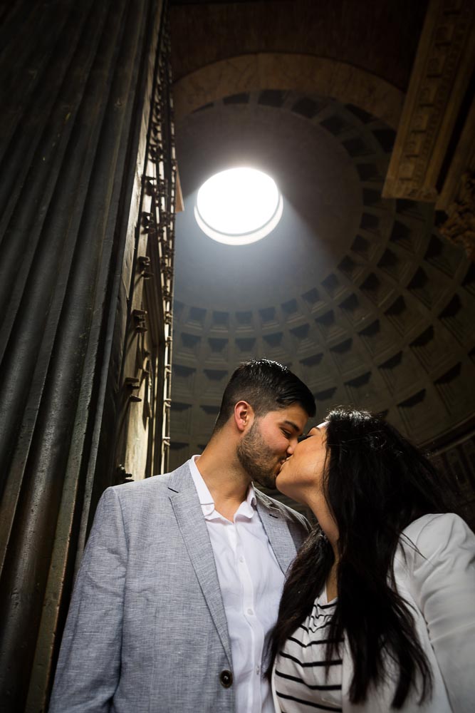 Engagement session in Rome. Kissing underneath the light from the Roman Pantheon hole