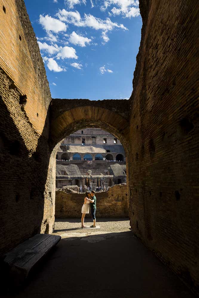 Picture taken from afar of a coupe underneath an ancient roman arch