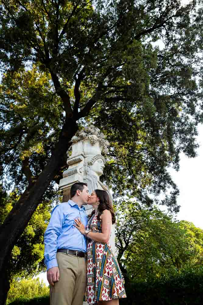 Kissing under statue and tree