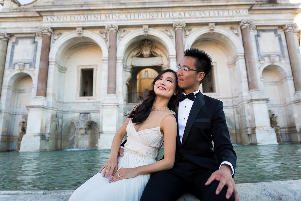 The bride rests against the groom's shoulder while sitting on the Gianicolo water fountain