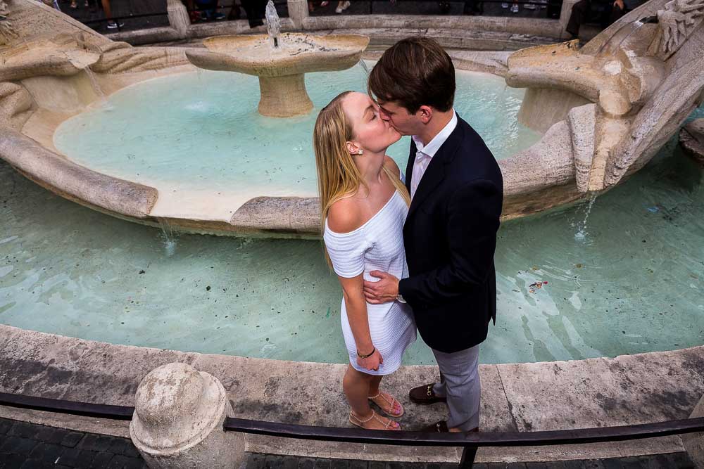 Romantically kissing by a water fountain at the bottom of the Spanish steps