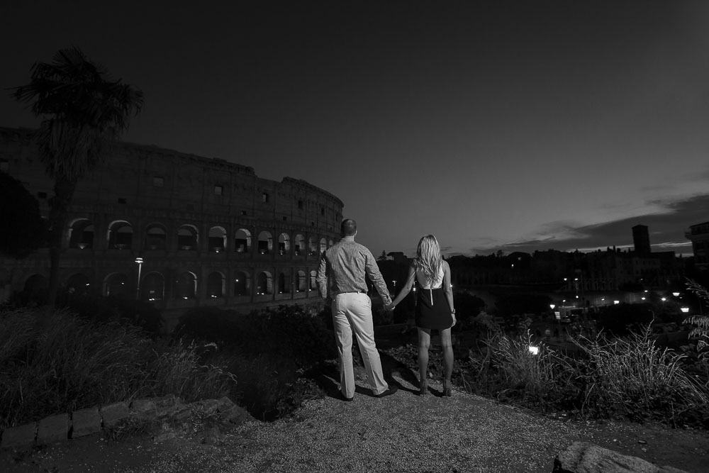 Black and white photo of an engaged couple looking at the Colosseum