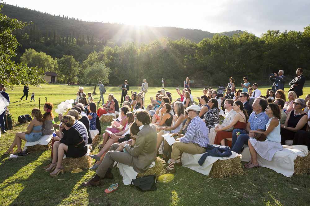 The wedding guests sitting outside in a filed