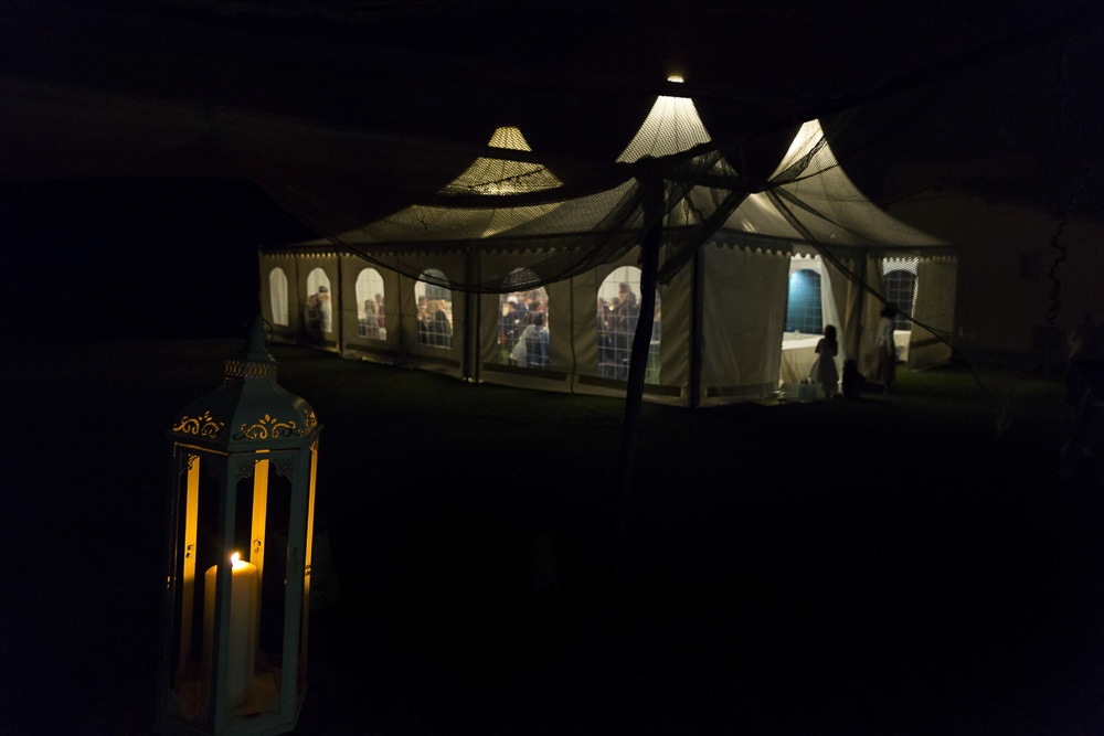 Night time view of the dinner tent lit up in the dark. Wedding in Tuscany Italy