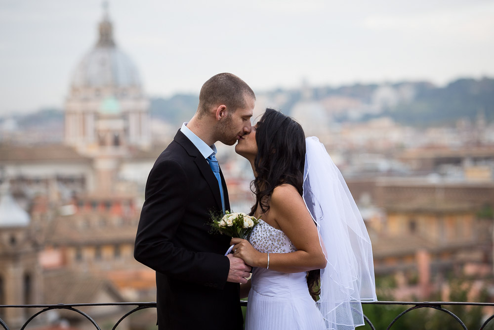 Newlywed couple kissing in front of the city of Rome